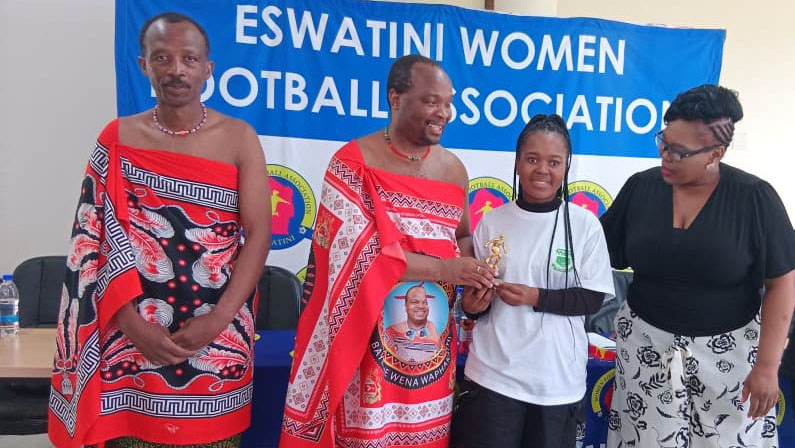 The Player of the Season Lindelwa Sihlongonyane receiving her trophy from MP Welcome Dlamini (2nd L) and EWFA Vice Chairperson Cindy Dludlu, while Sibusiso ‘Mathende’ Mkhatshwa (L) looks on.