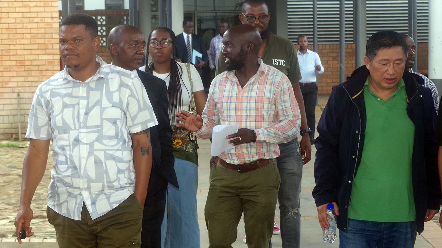 Jin Houyun (R) leaving the Mbabane Magistrates Court with the police investigating team, interpreter and his defence counsel after his remand.