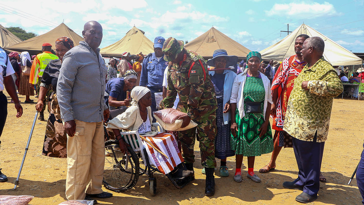 Major General Thembinkosi Mngometulu presenting a pack of beans and rice to an elderly woman during the mini army day at Mpaka, courtesy of Their Majesties. (Pic: Joseph Zulu)