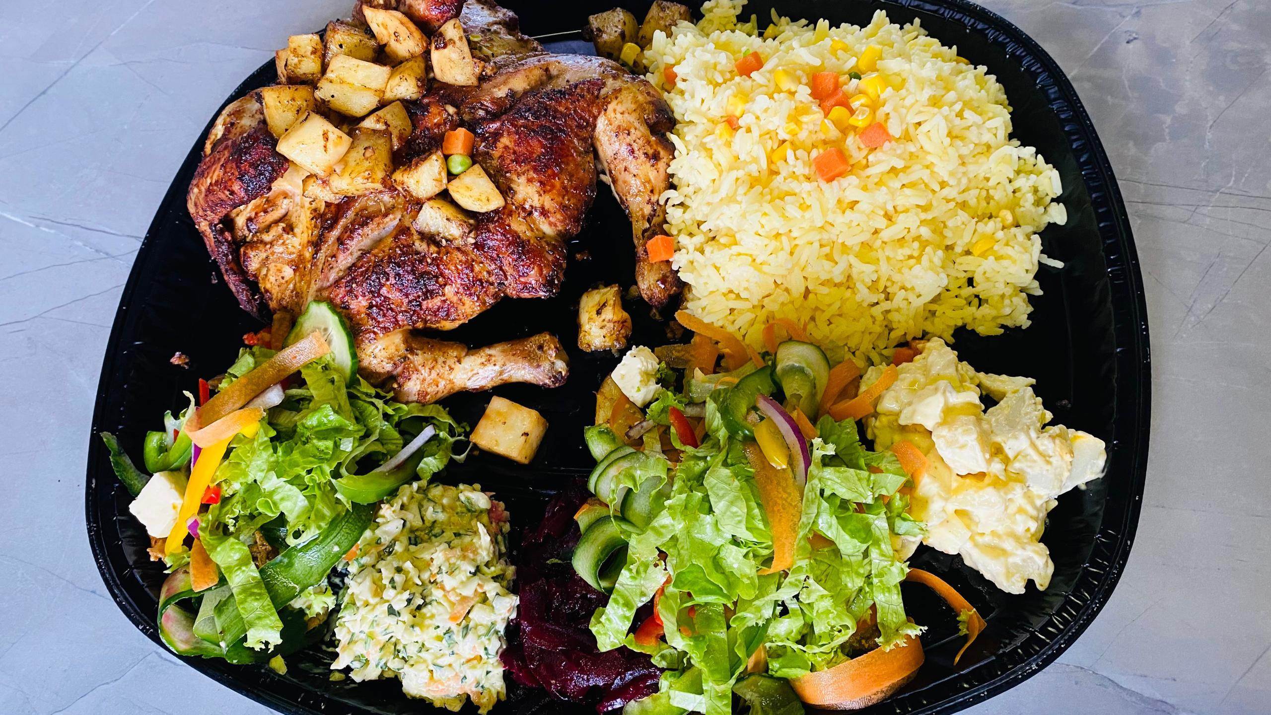 A platter of perfectly grilled chicken, golden-brown roasted potatoes and a colourful array of fresh salads and sides, all ready to be enjoyed.