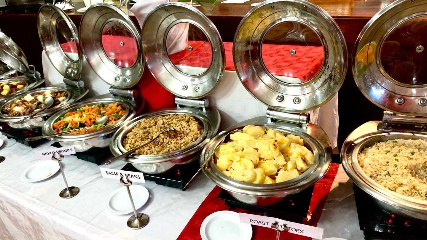 Sample a little bit of everything! Enjoy a generous spread of delicious dishes including roast potatoes, mixed veggies, and savory rice.