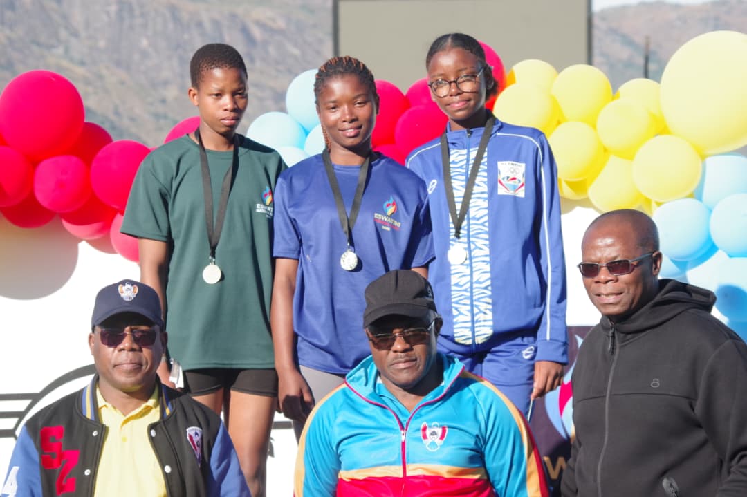 Girls’ 100m medallists (back row L-R) Eswatini’s Thandiwe Metiso, Yoliswa Simelane and Seychelles’ Aaliyah Nicette receive their medals from National Games LOC Chairman Zakhele Dlamini (R), Sports Council’s Dan Mavuso (C) and Eswatini National Olympic Committee Treasurer Zakhele Zulu. (Pic:Nimrod Hlophe)